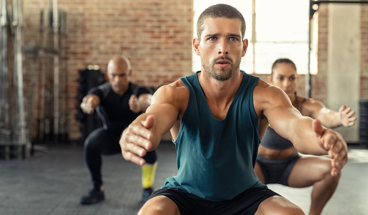Fitness man squatting with class at gym